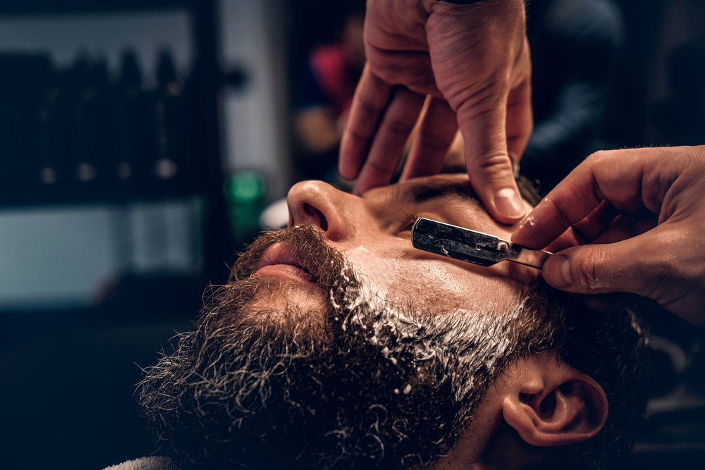 Barber shaving bearded male with a sharp razor. - Gimle Parfymeris blogg